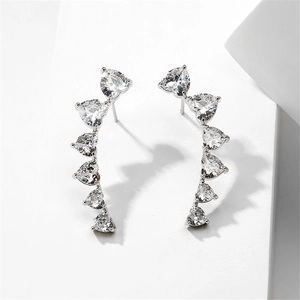 Macro shot of silver ear climbers with gradient heart-shaped cubic zirconia on white stone