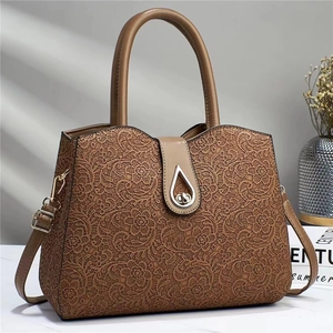 Detailed view of brown lace embroidery handbag with golden teardrop metal lock and handle