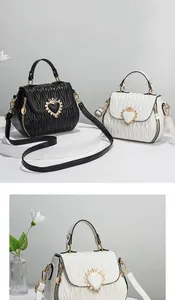 Close-up of shell-shaped shoulder bag with quilted embroidery and gold heart crown clasp