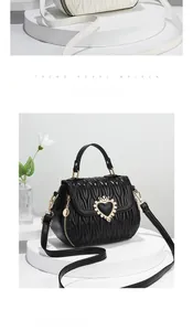 Detail of black quilted shell bag with heart crown metal clasp and texture finish