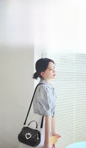 Quilted shell-shaped crossbody bag with heart diamond buckle shown on shoulder