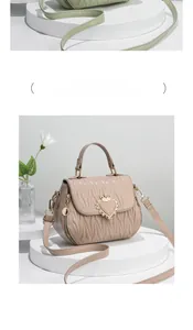 Close-up of khaki shell-shaped shoulder bag with quilted pleats and crown heart charm