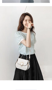 Detail of white quilted shell-shaped shoulder bag with gold heart clasp and top handle