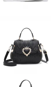 Detail view of black quilted faux leather handbag with golden crown heart buckle and texture