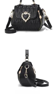 Detail of black quilted shell bag showing wave stitching and golden heart crown buckle