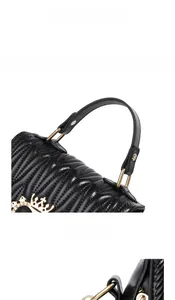 Detail of black quilted leather shell bag with gold crown logo and fine stitching handle