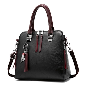 Black pebbled faux leather tote bag with dark red handles and a silver cat charm