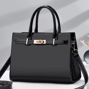 Sac Boston chic en cuir verni noir avec ferrures dorées et surpiqûres blanches contrastées