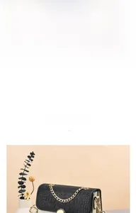 Detail of crocodile embossed leather flap and golden chain handle on two-tone crossbody bag
