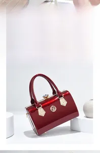 Detailed macro of dark red patent leather bag with gold floral clasp and crystal top