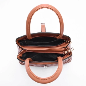 Detail view of brown quilted leather handbag featuring double gold zipper compartments