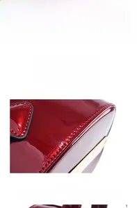 Detail shot of the reinforced stitching on the glossy patent leather bag's bottom