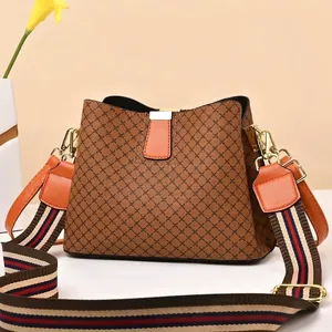 Close-up of brown quilted bucket bag with colorful striped wide strap and gold hardware