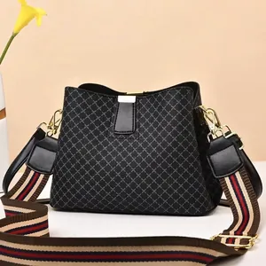 Detail of quilted leather bucket bag with striped wide shoulder strap and gold hardware