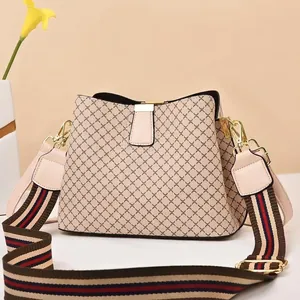 Detail of beige bucket bag with diamond lattice pattern and striped canvas shoulder strap