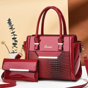 Ensemble sac à main rouge texture crocodile et pochette avec logo doré sur fond beige