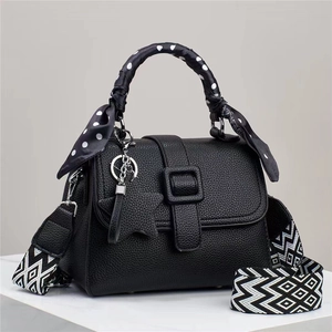 Détail du sac à main noir grainé avec poignée foulard à pois et pendentif en étoile