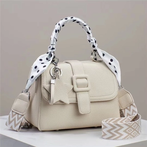 Détail du sac à main crème en cuir litchi avec poignée foulard à pois et pendentif étoile