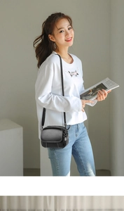 Detail of black pebbled leather crossbody bag with three zipper compartments and strap