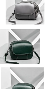 Detail view of multi-layer grey and green crossbody bags with white contrast stitching