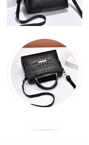 Detail of black crocodile embossed leather handbag with silver hardware and metal handle