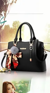 Détail d'un sac cabas en cuir noir avec pompon gris et breloque en ruban de soie imprimé