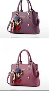 Détail d'un sac cabas en cuir rose poudré avec pompon décoratif et foulard en soie imprimé