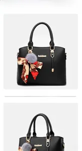 Détail du sac à main noir en cuir grainé avec foulard en soie et pompon gris en peluche