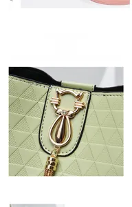 Détail du sac matelassé vert clair avec un pendentif chat doré orné de strass brillants
