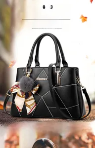 Détail du sac à main noir avec coutures contrastées, logo métal et poignée en foulard