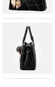 Détails du sac à main noir avec surpiqûres géométriques et pendentif pompon gris doux