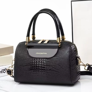 Elegant black lizard-textured bucket bag with golden hardware on marble surface
