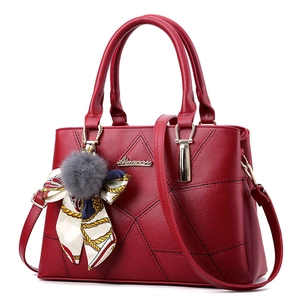 Détail du sac à main rouge matelassé avec pompon en peluche et foulard en soie décoratif