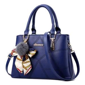 Détail du sac à main bleu foncé en simili cuir avec matelassage et finitions dorées