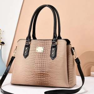 Sac à main beige motif lézard chic avec poignées noires et détails dorés sur fond épuré
