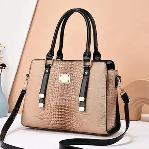 Detail of beige lizard texture leather bag with black handles and golden metal hardware