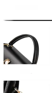 Close-up of comfortable leather handle with fine stitching and golden metal clasp on black bag