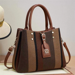 Detail der gestreiften gewebten Handtasche mit Ledergriffen und Metallnieten-Akzenten