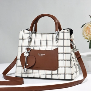 Plaid pattern tote bag with leather handles and heart pendant on a stone surface