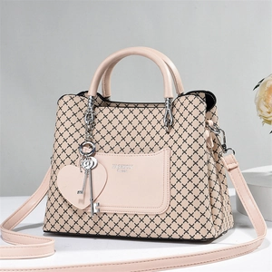 Detail of nude pink tote with black X patterns and heart charm pendant on side