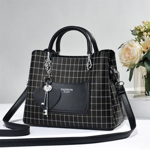 Detailed shot of black and white checkered handbag with Fashion Queen print and heart charm