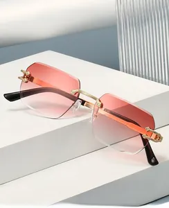 Detailed close-up of rimless gradient pink lenses with gold metal temples on geometric stand
