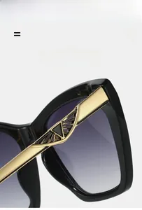 Macro view of black cat-eye sunglasses featuring golden metal accents on the temple hinges