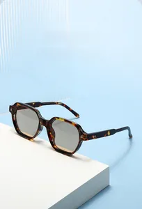 Detail of tortoise shell geometric sunglasses with metal rivets on a white pedestal