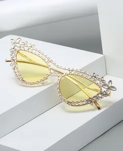 Vista macro della montatura cat-eye dorata con strass bianchi e dettagli con motivo floreale