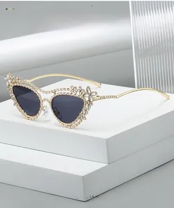 Dettaglio degli occhiali da sole cat-eye dorati con montatura di strass e decori floreali