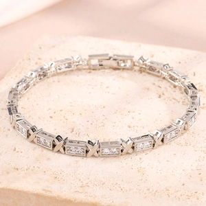 Detail of silver X-link tennis bracelet featuring pavé-set white zircons on stone background