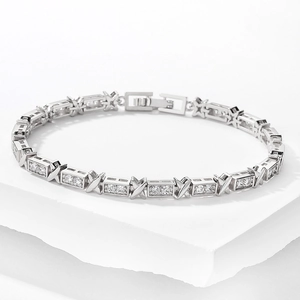 Detail of silver-tone X-shaped bracelet with cubic zirconia on white stone stand