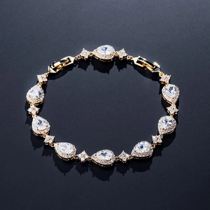 Elegant gold bracelet with pear-shaped white zircons and floral link accents on black