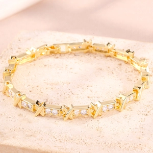 Luxurious gold plated X-link bracelet with sparkling crystals on a textured stone surface